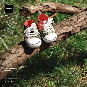 Puede incluir: Zapatillas de bebé con un estampado floral en rojo, verde y blanco. Los zapatos tienen cordones blancos, una puntera blanca y un interior rojo. Se exhiben sobre una rama de árbol marrón sobre un fondo de hierba y follaje verdes.