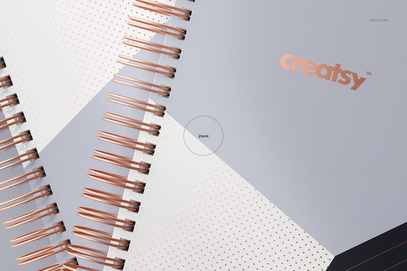 Op de afbeelding: Een close-up van een spiraalgebonden notitieboek met een ros&eacute;gouden draadbinding. De omslag is een geometrisch ontwerp met witte, grijze en zwarte secties. Het woord "creatsy" is in ros&eacute;goud gedrukt op de grijze sectie.