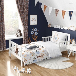 Puede incluir: Una cama de ni&ntilde;o peque&ntilde;a de color blanco con un edred&oacute;n a cuadros azules y blancos y una s&aacute;bana con estampado blanco y marr&oacute;n. La ropa de cama presenta un oso panda, p&aacute;jaros y hojas. La cama est&aacute; contra una pared azul oscuro con un marco de madera blanco. Hay cortinas marrones con patrones florales blancos en el lado izquierdo de la imagen. La pared tambi&eacute;n tiene un cuadro blanco enmarcado con un arco&iacute;ris y la palabra "Home" en letras blancas en un estante sobre la cama.