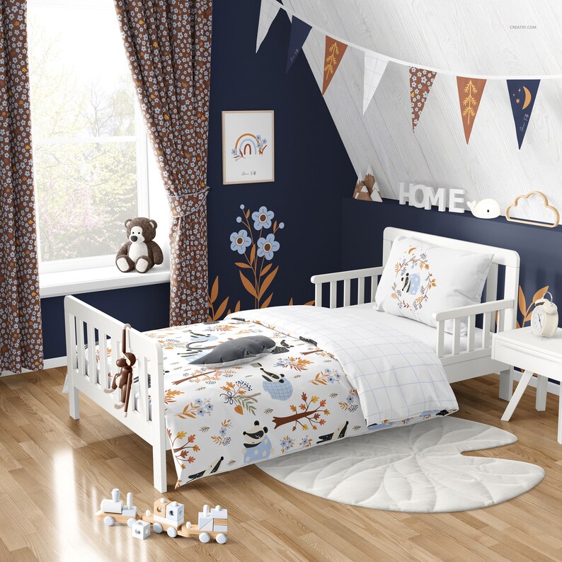 Puede incluir: Una cama de ni&ntilde;o peque&ntilde;a de color blanco con un edred&oacute;n a cuadros azules y blancos y una s&aacute;bana con estampado blanco y marr&oacute;n. La ropa de cama presenta un oso panda, p&aacute;jaros y hojas. La cama est&aacute; contra una pared azul oscuro con un marco de madera blanco. Hay cortinas marrones con patrones florales blancos en el lado izquierdo de la imagen. La pared tambi&eacute;n tiene un cuadro blanco enmarcado con un arco&iacute;ris y la palabra "Home" en letras blancas en un estante sobre la cama.