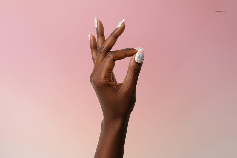 May include: A dark hand with long, white, oval-shaped nails. The thumb and index finger are touching, forming a circle. The background is a gradient of pink and peach.