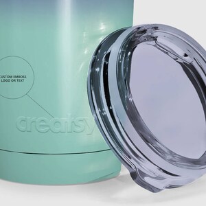 May include: A teal and blue stainless steel tumbler with a clear lid. The tumbler has a white logo that says "creaisy" and the text "Custom Emboss Logo or Text".