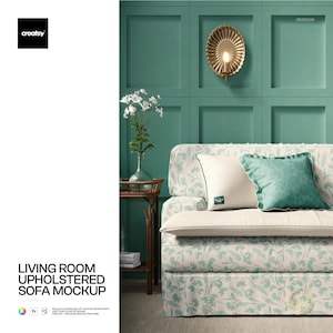 May include: A living room sofa mockup with a floral pattern in light blue and cream. The sofa has two decorative pillows, one cream and one teal. The background is a teal wall with a gold wall sconce and a small side table with a vase of white flowers.