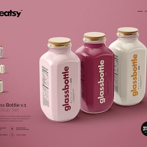 May include: Three glass bottles with gold lids and labels that say "glassbottle" in a yellow font. The bottles are filled with pink, red, and white liquids. The bottles are on a pink surface.