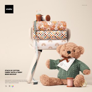 May include: A teddy bear wearing a green sweater sits next to a stack of patterned cotton fabric rolls. A measuring tape is draped over the fabric. The fabric rolls feature floral, checkered, and rainbow designs. A spool of thread and a pin cushion are also present.