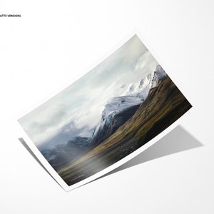 May include: A photograph of a mountain range with snow-capped peaks and a valley covered in green grass. The sky is cloudy and the mountains are in the distance.