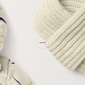 Op de afbeelding: Een witte gebreide sjaal met een bruin leren patch waarop "EST LOVE" staat.