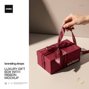 以下が含まれることがあります： 「branding drops」と「x&ribbon」の文字が入った、バーガンディ色のギフトボックスとそれに合わせたリボン。ボックスは長方形でサテン仕上げ。リボンは上部でリボン結びになっています。画像には「LUXURY GIFT BOX WITH RIBBON MOCKUP」の文字も含まれています。