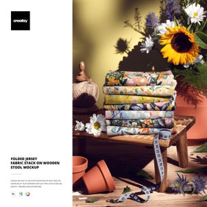 Puede incluir: Una pila de tela de punto plegada con estampados florales se encuentra sobre un pequeño taburete de madera. La tela es de varios colores, incluyendo amarillo, rosa y azul. Una cinta métrica está colocada sobre el taburete. La imagen también incluye flores y macetas de terracota.