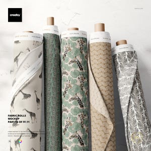 May include: Five fabric rolls with diverse patterns, including giraffes, leaves, and geometric designs. The rolls are labelled "Magic Jungle" and "Julia Dreams." The fabric colours include beige, green, and brown. The text "Fabric Rolls Mockup Part 16 of FF.11" is visible.