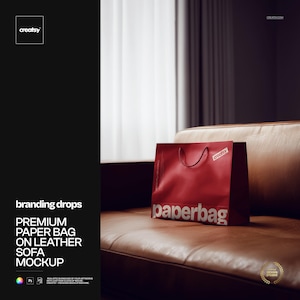 Puede incluir: Una bolsa de papel roja con la palabra "paperbag" impresa, colocada sobre un sofá de cuero marrón. La bolsa tiene un asa y el logotipo "creatsy". La imagen es una maqueta para "branding drops".