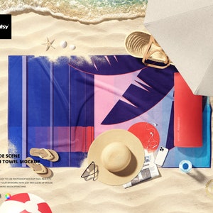 Może przedstawiać: Makieta ręcznika plażowego z niebieskim i różowym wzorem. Ręcznik leży na piaszczystej plaży z słomkowym kapeluszem, okularami przeciwsłonecznymi, telefonem i butelką wody. Tekst "Seashore Scene Beach Towel Mockup" znajduje się w górnej części obrazu.