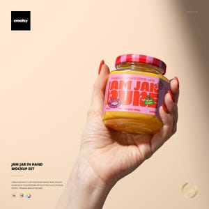 May include: A hand holding a jar of jam with a pink and purple label. The label says "JAM JAR PURE" and "Family Owned Since 1978". The jar has a red and white checkered lid and contains 400g of jam. The jar is filled with a yellow preserve.