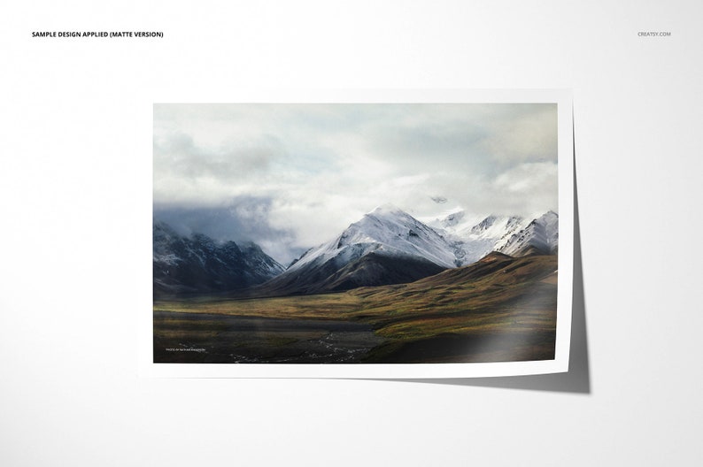 May include: A panoramic view of a snow-capped mountain range with a valley in the foreground. The mountains are covered in white snow and the valley is covered in green grass. The sky is cloudy and the clouds are casting shadows on the mountains.