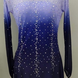 May include: A long-sleeved, ombre skating dress with a light blue to dark blue gradient. The dress is covered in small, clear rhinestones.