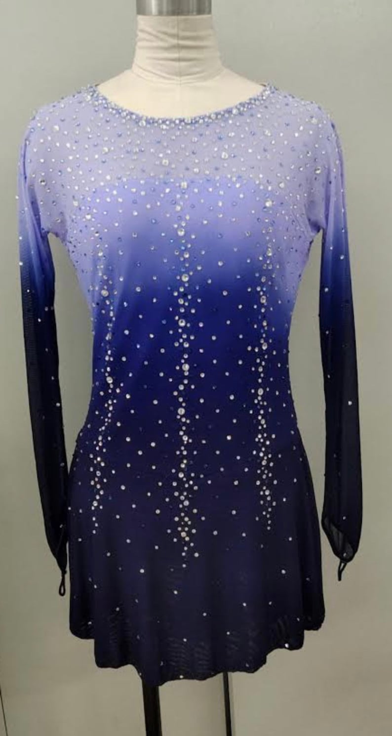 May include: A long-sleeved, ombre skating dress with a light blue to dark blue gradient. The dress is covered in small, clear rhinestones.