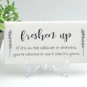 May include: White ceramic tile with black text that reads "freshen up" and "If it's in the cabinet or drawers, you're welcome to use it like it's yours."