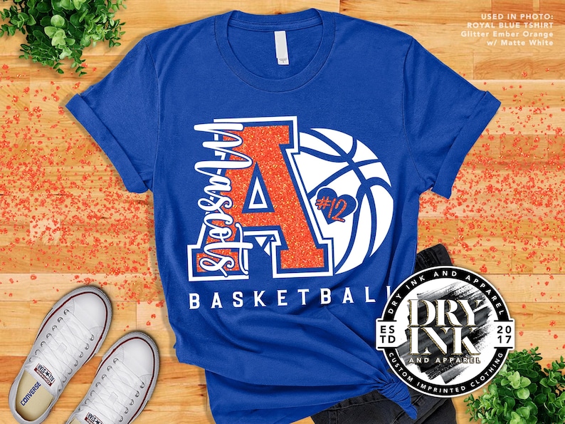 laying flat is a royal blue tshirt by bella and canvas 3001 with a custom glitter basketball mom design in the color glitter ember orange and matte white