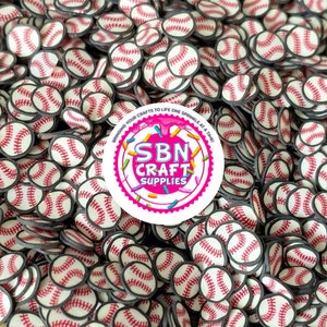 May include: A close-up shot of a pile of baseball-shaped craft supplies. Each baseball is white with red stitching and a black border. A circular sticker with the text "SBN Craft Supplies" is visible.
