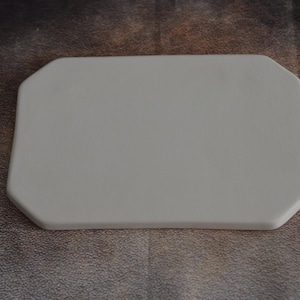 Può includere: Un sottobicchiere in ceramica bianco ottagonale con una finitura liscia e opaca.