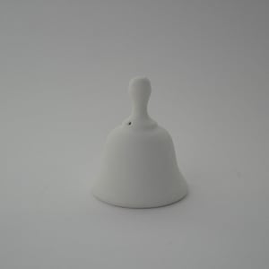 Può includere: Una piccola campana in ceramica bianca con la parte superiore arrotondata e un piccolo foro al centro.