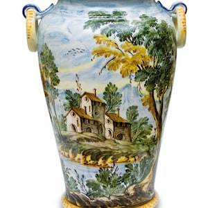 Può includere: Un grande vaso in ceramica blu e bianca con due manici. Il vaso è decorato con una scena dipinta di un paesaggio campestre con case, alberi e montagne.