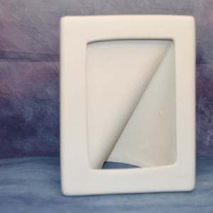Może przedstawiać: Prostokątna, biała ramka na zdjęcia z zakrzywionym wnętrzem. Ramka ma gładkie, matowe wykończenie i nowoczesny design. Tło to mieszanka niebieskiego i fioletowego.