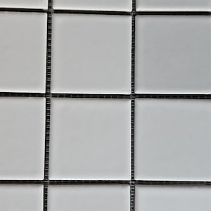 Peut inclure: Gros plan sur une feuille de carrelage en mosaïque. Les carreaux sont carrés, blancs et disposés en grille. Les joints sont gris foncé, créant un contraste avec les carreaux clairs. Cette feuille de carrelage convient à divers projets de rénovation.