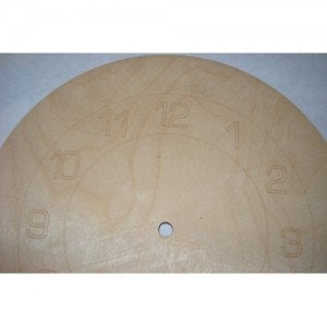 May include: A blank, beige, round clock face with black numbers 1 through 12. The clock face has a small hole in the center for the clock hands.