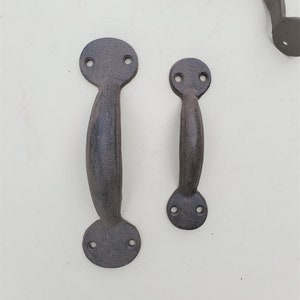 May include: Two cast iron door handles with a dark brown finish. The larger handle is approximately 6 inches tall and the smaller handle is approximately 4 inches tall.