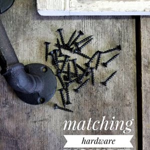 May include: Black metal door handle with matching screws included. The handle is made of pipe and has a rounded end. The screws are scattered on a wooden surface.