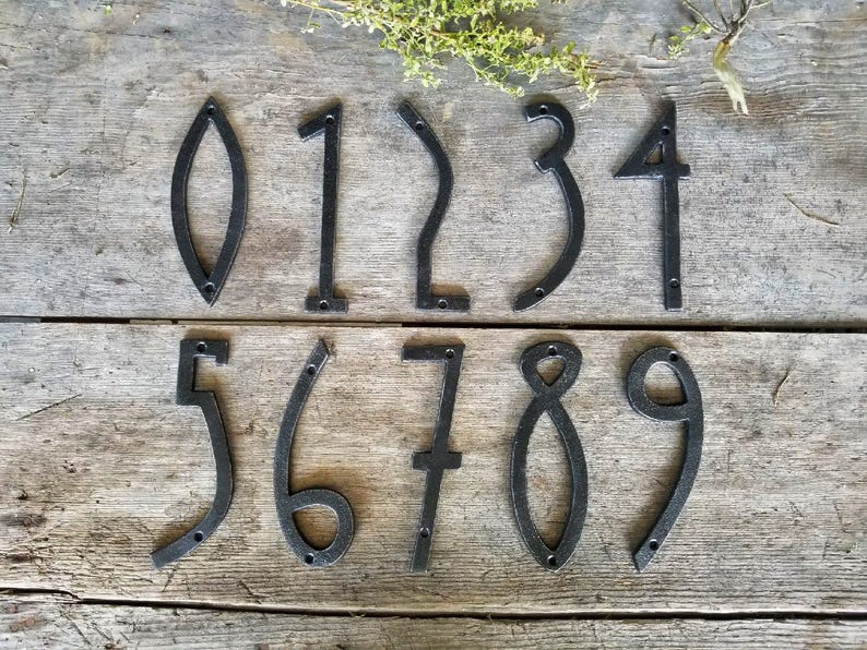 May include: Ten black metal house numbers, 0 through 9, with a unique, modern design. Each number is individually crafted and features a simple, elegant silhouette.