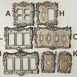 Könnte beinhalten: Satz von acht dekorativen Wandplatten in Gold mit verzierten Designs. Die Platten verfügen über verschiedene Konfigurationen von Lichtschalteröffnungen.