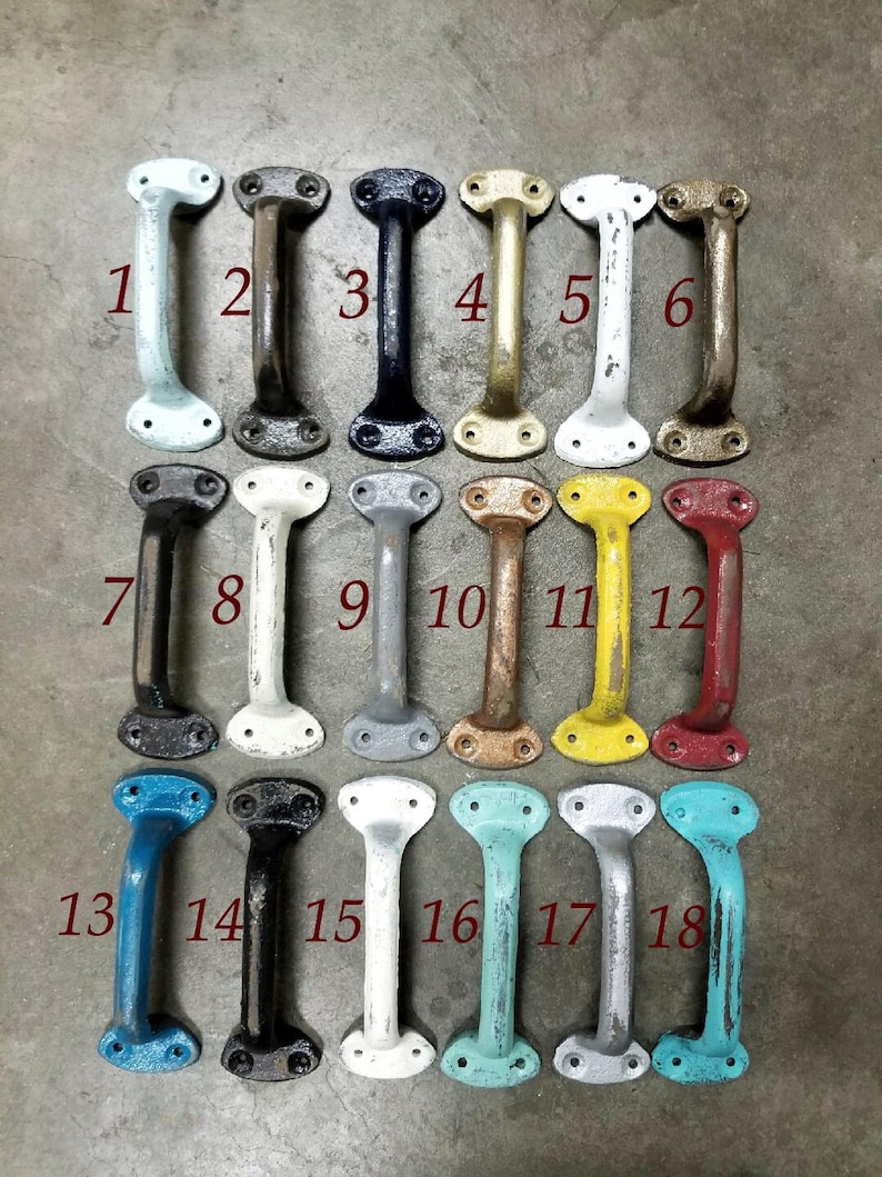 May include: Eighteen cast iron drawer pulls in a variety of colours. The pulls are all the same shape, with a rounded top and bottom and a straight handle in the middle. The pulls are arranged in three rows of six, with each row showing a different colour.