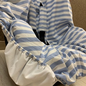 A blue and white striped car seat cover with elastic around the edges. The cover is made of a soft, breathable fabric and is designed to protect your car seat from spills, dirt, and wear and tear.