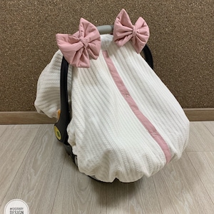 Funda para asiento de coche con faldón elástico para niña en piqué color crema y forro con lazos color rubor, funda personalizada para asiento de coche