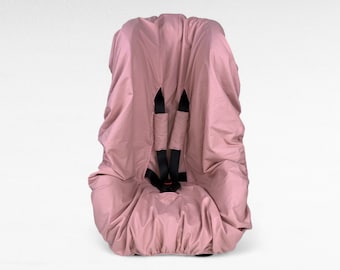 Könnte beinhalten: Ein rosa Autositzbezug mit schwarzen Gurten. Der Bezug ist aus einem weichen, atmungsaktiven Stoff gefertigt und soll Ihren Autositz vor Verschüttungen, Schmutz und Abnutzung schützen.