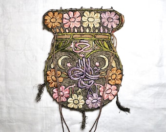 May include: An antique embroidered pouch with a floral design in shades of orange, pink, and yellow. The pouch features intricate stitching, a drawstring closure, and decorative tassels. The background is a white fabric.