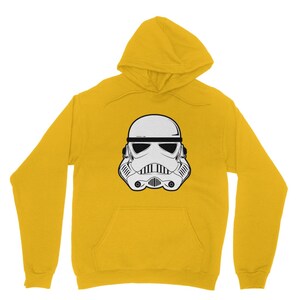 Puede incluir: Una sudadera con capucha amarilla con un gr&aacute;fico blanco y negro de un casco de Stormtrooper.