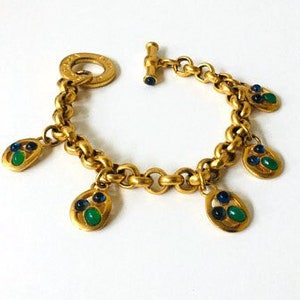 Peut inclure: Bracelet en chaîne dorée avec des breloques en pierres précieuses vertes et bleues. Le bracelet a un fermoir à bascule.