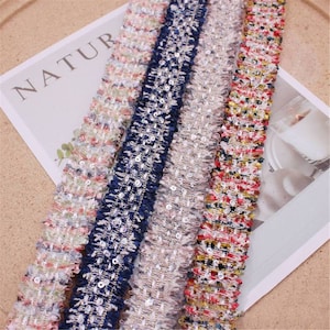 Pode incluir: Quatro guarnições diferentes com uma borda texturizada desfiada e lantejoulas. As guarnições são rosa, azul, cinza e vermelho.