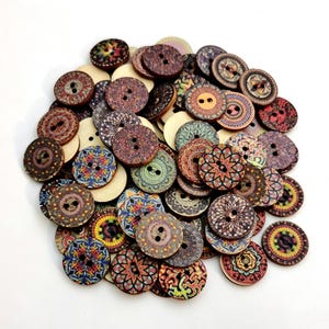 May include: A large collection of round wooden buttons featuring a variety of colorful, intricate printed patterns. Each button has two holes in the center. The designs include geometric shapes, floral motifs, and mandala-style patterns in many colors.