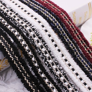 May include: Assortment of black, white, red, and blue trim with a gold thread running through each. The trim has a fuzzy texture and is ideal for adding a decorative touch to clothing, crafts, and home decor projects.