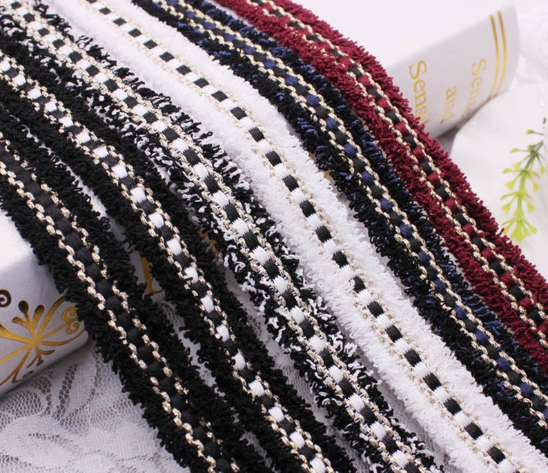 May include: Assortment of black, white, red, and blue trim with a gold thread running through each. The trim has a fuzzy texture and is ideal for adding a decorative touch to clothing, crafts, and home decor projects.
