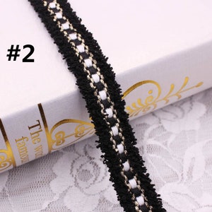 May include: Black and white trim with a gold thread running through it. The trim has a fuzzy texture.