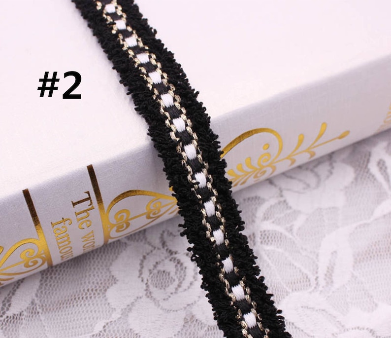 May include: Black and white trim with a gold thread running through it. The trim has a fuzzy texture.