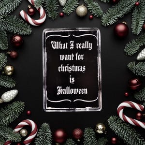 May include: A black sign with white text that reads "What I really want for christmas is Halloween". The sign is surrounded by Christmas decorations, including pine branches, ornaments, and candy canes.
