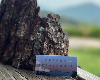 May include: A sticker with a blue and purple mountain range design. The text "SOUTHERN APPALACHIA" is printed in black on the sticker.