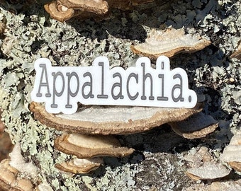 May include: A close-up of a tree trunk with a white sticker that says "Appalachia." The tree trunk is covered in brown and gray lichen.