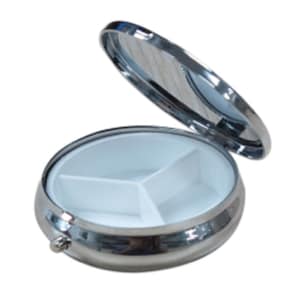 Puede incluir: Un pastillero ovalado de color plateado con tapa abatible y espejo. El interior est&aacute; dividido en tres compartimentos blancos. El pastillero est&aacute; abierto.